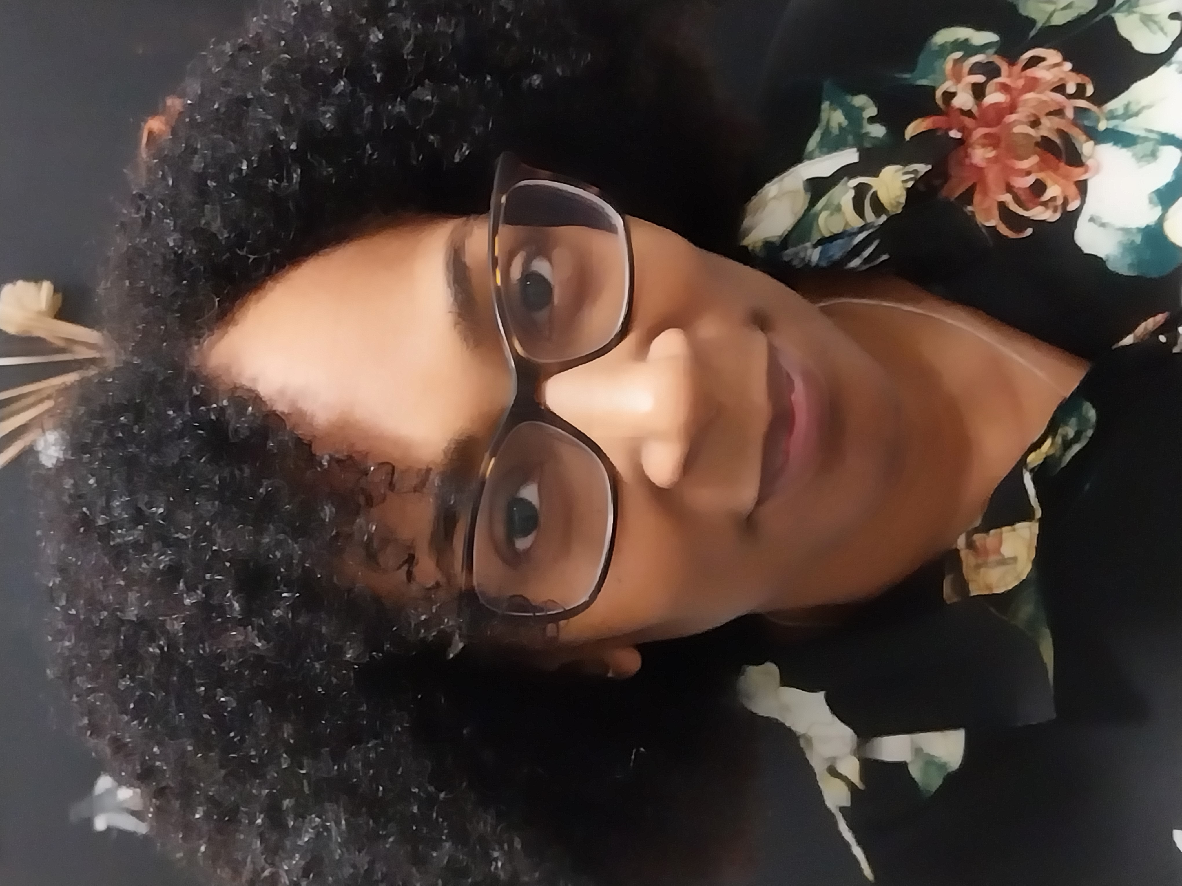 A selfie of Maxine binger, a Black woman smiling and wearing glasses.